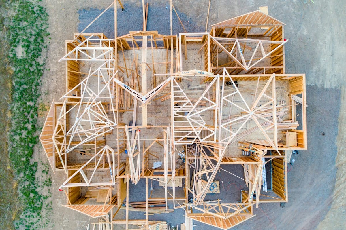 Aerial view of a wood-framed house under construction, roof trusses set across the floor plan