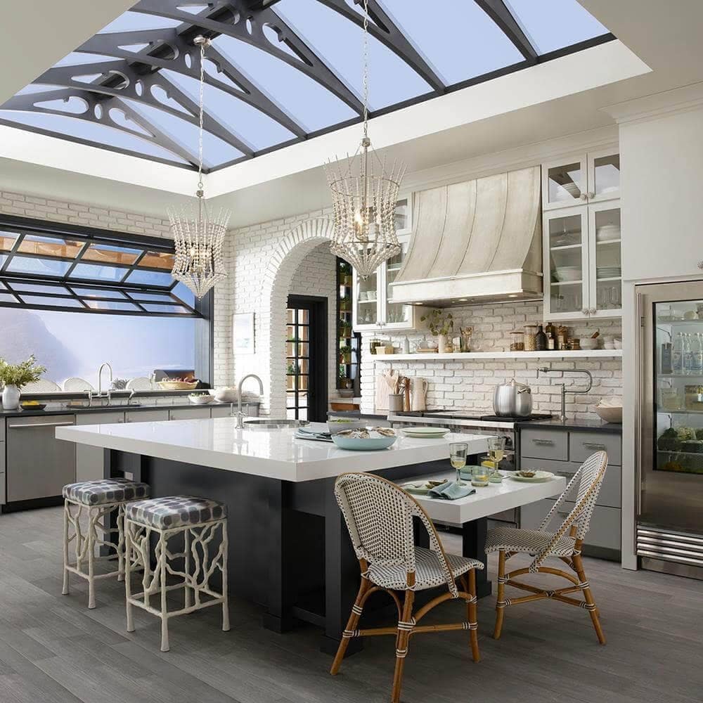 garden kitchen with vaulted ceiling kitchen island beautiful wood flooring white beaded hanging lights, garage style window, custom counterstools, greenhouse kitchen