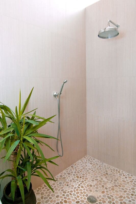 Warm modern master bath with walk in shower and pebble flooring