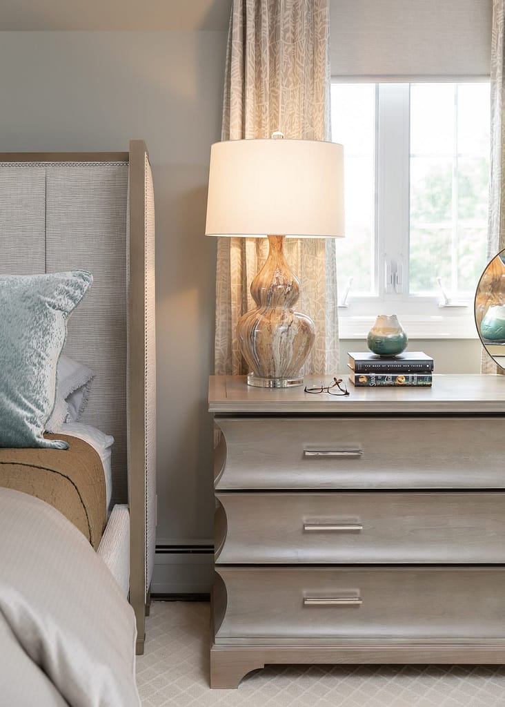 neutral colored bedding, light and airy master bedroom, light wood night stand, accent lamp